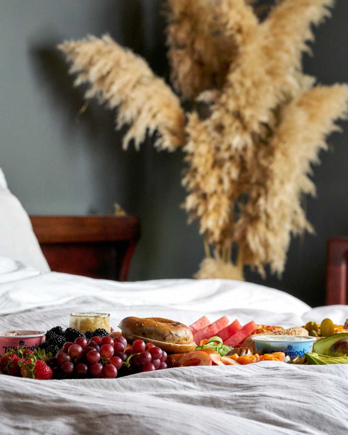 Breakfast board in a bed with pampas grass.