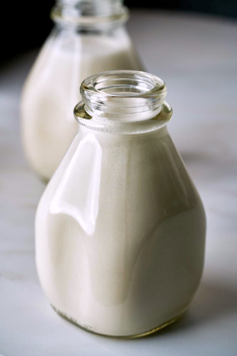 Two glass jugs of oat milk.