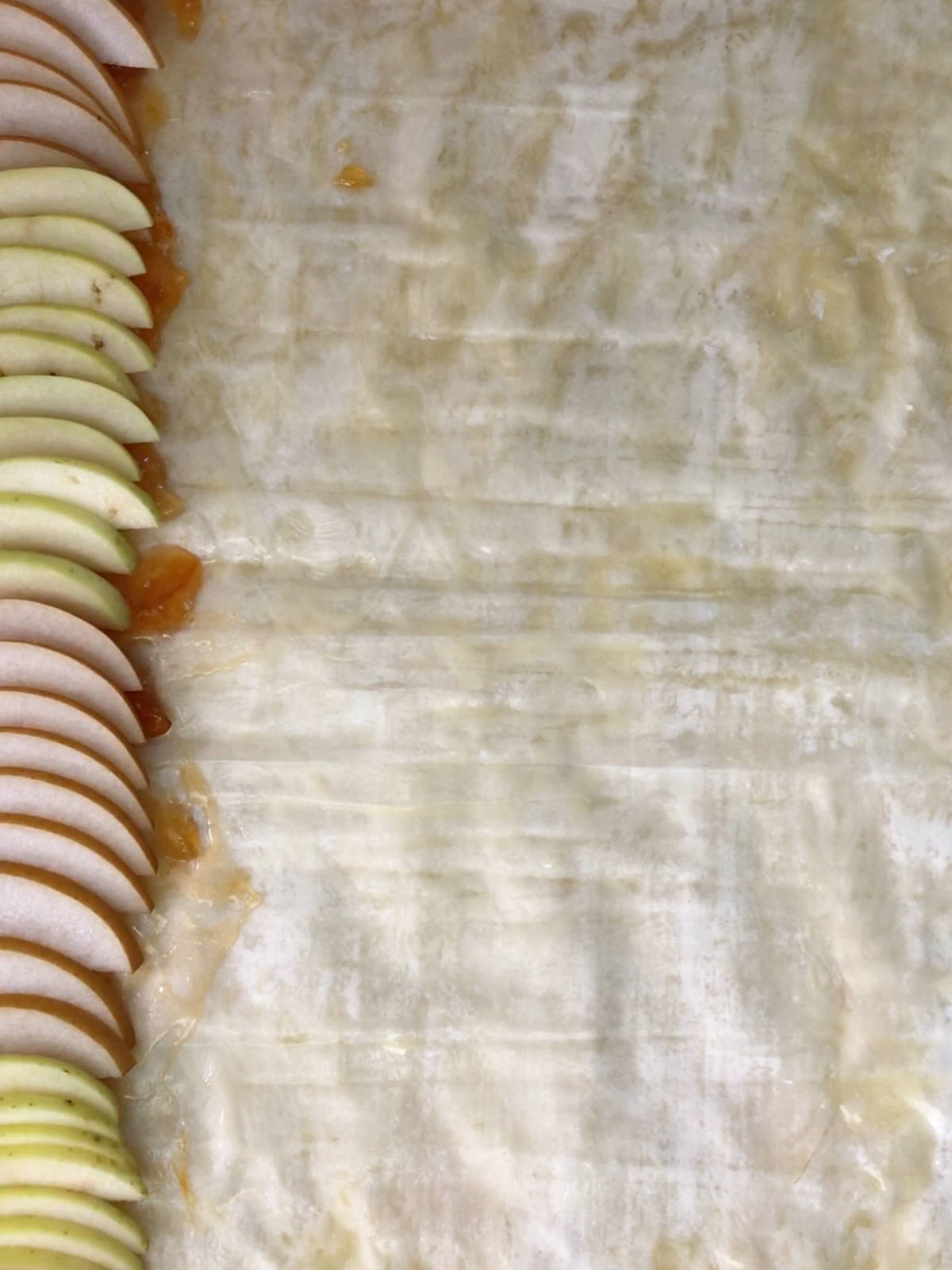 Sliced apples stacked on the side of a layer of phyllo dough.