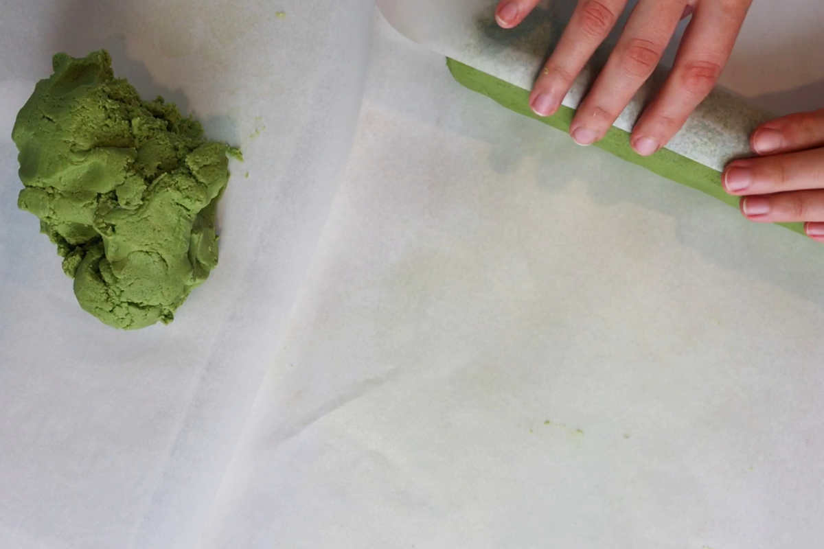 Rolling green dough on parchment paper.