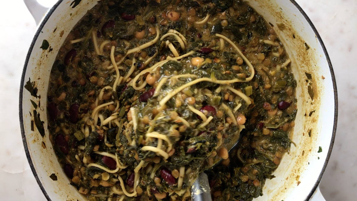 Green noodle soup in a pot.