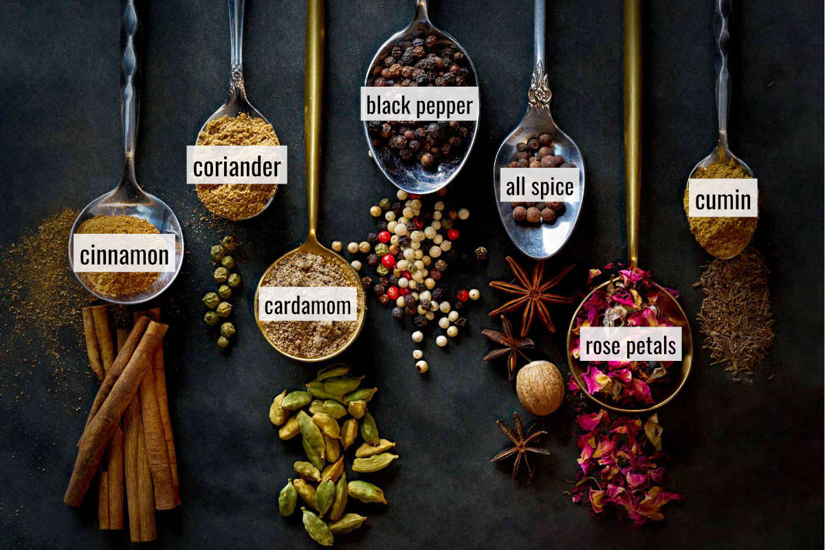 Labeled ground and whole spices on and around spoons.