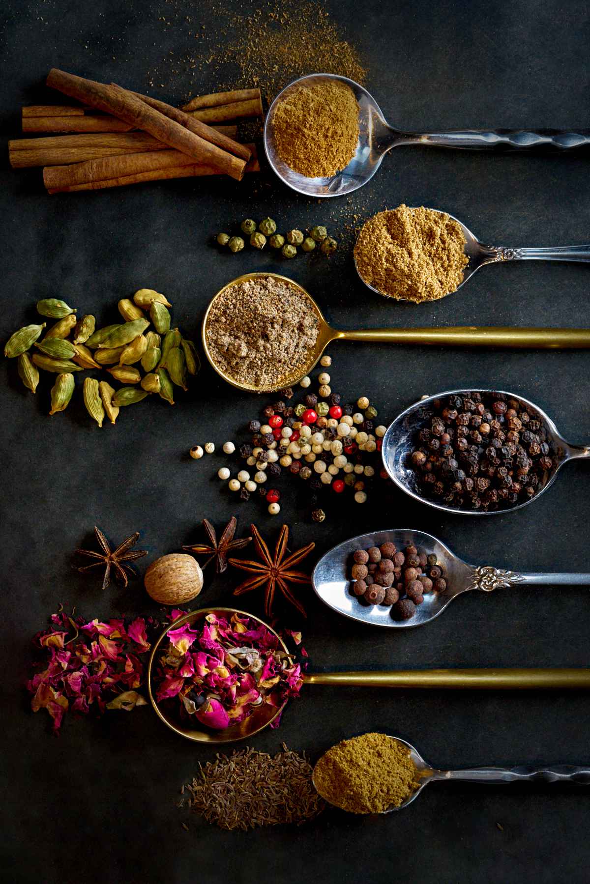 Ground and whole spices on and around spoons.