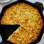 Shredded potato in a cast iron pan.