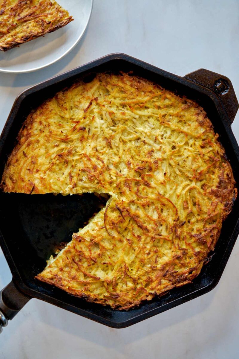 Shredded potato in a cast iron pan.