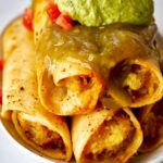 A stack of rolled tacos with guacamole and salsa.