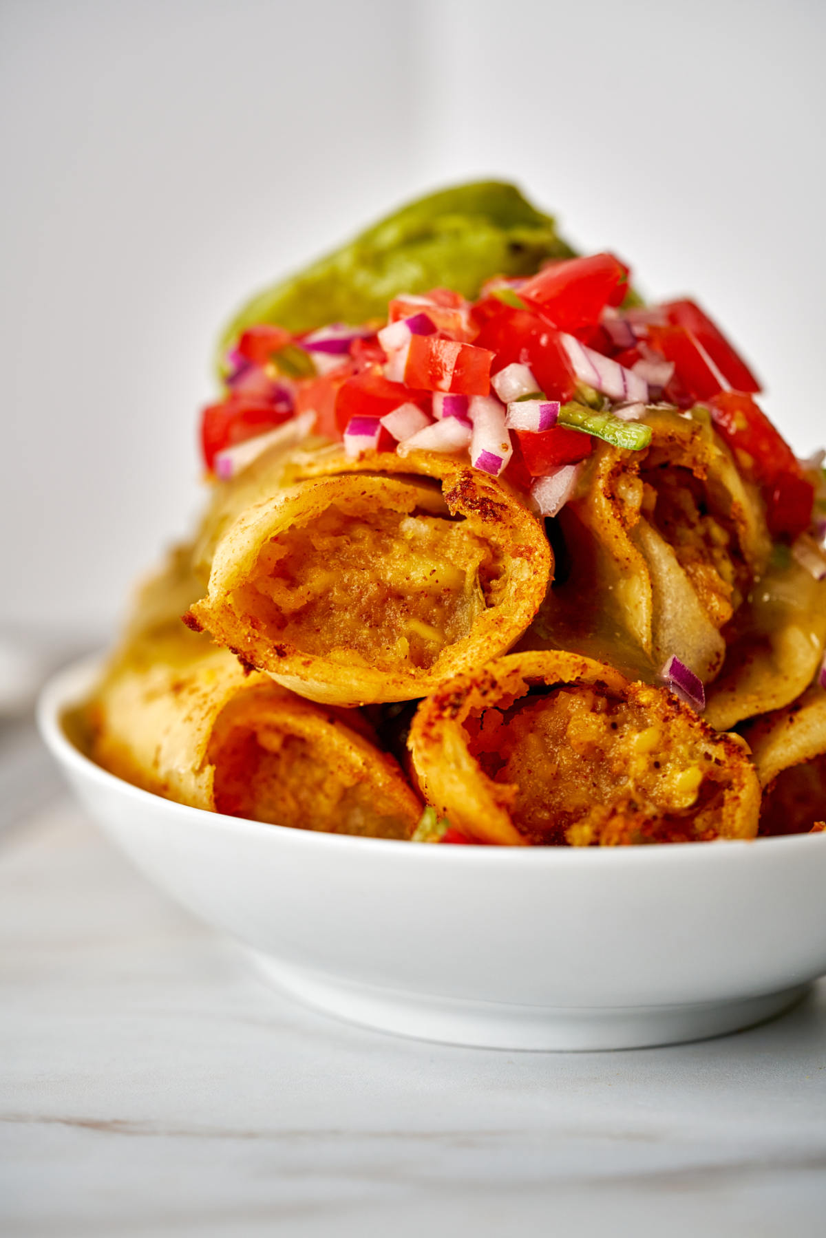 Front view of a stack of rolled tacos.