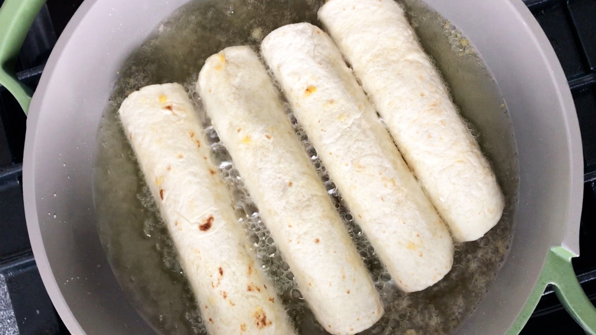 Rolled tortillas frying in oil.