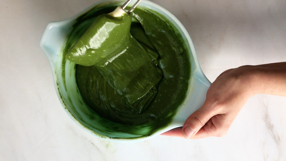 Melted green fudge in a mixing bowl with a rubber spatula.