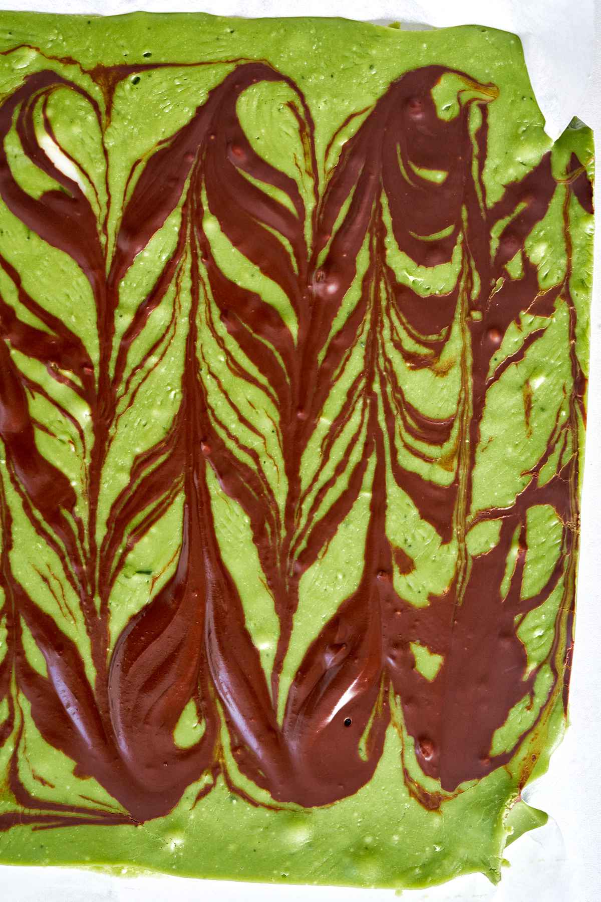 Slab of green chocolate with dark chocolate design.