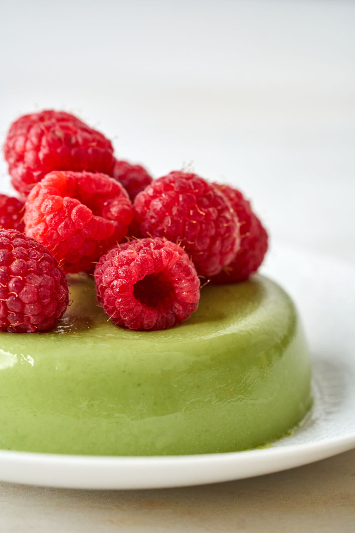 Green panna cotta topped with raspberries.