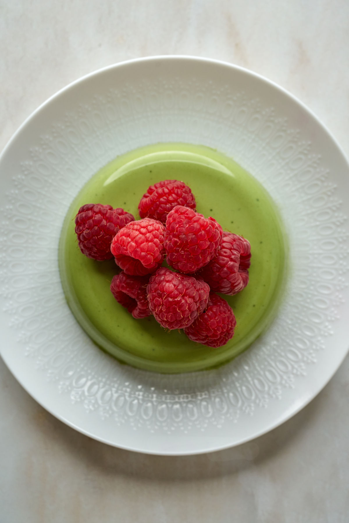 Green panna cotta with berries on top.