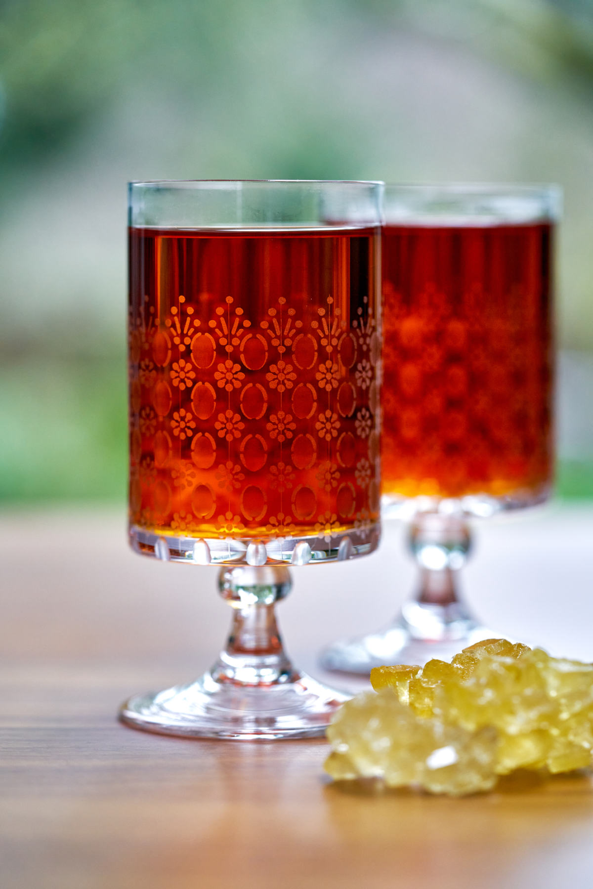 Two glasses of tea on a wood table.