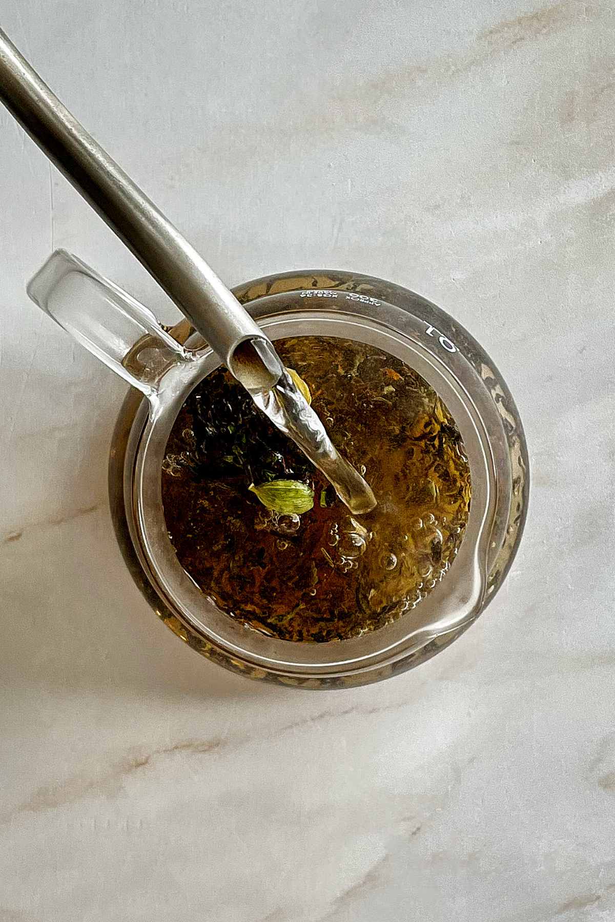 Pouring hot water into a glass teapot with tea.