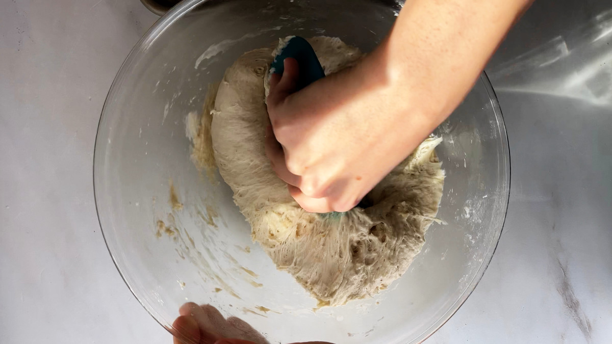 Folding dough in a glass bowl.