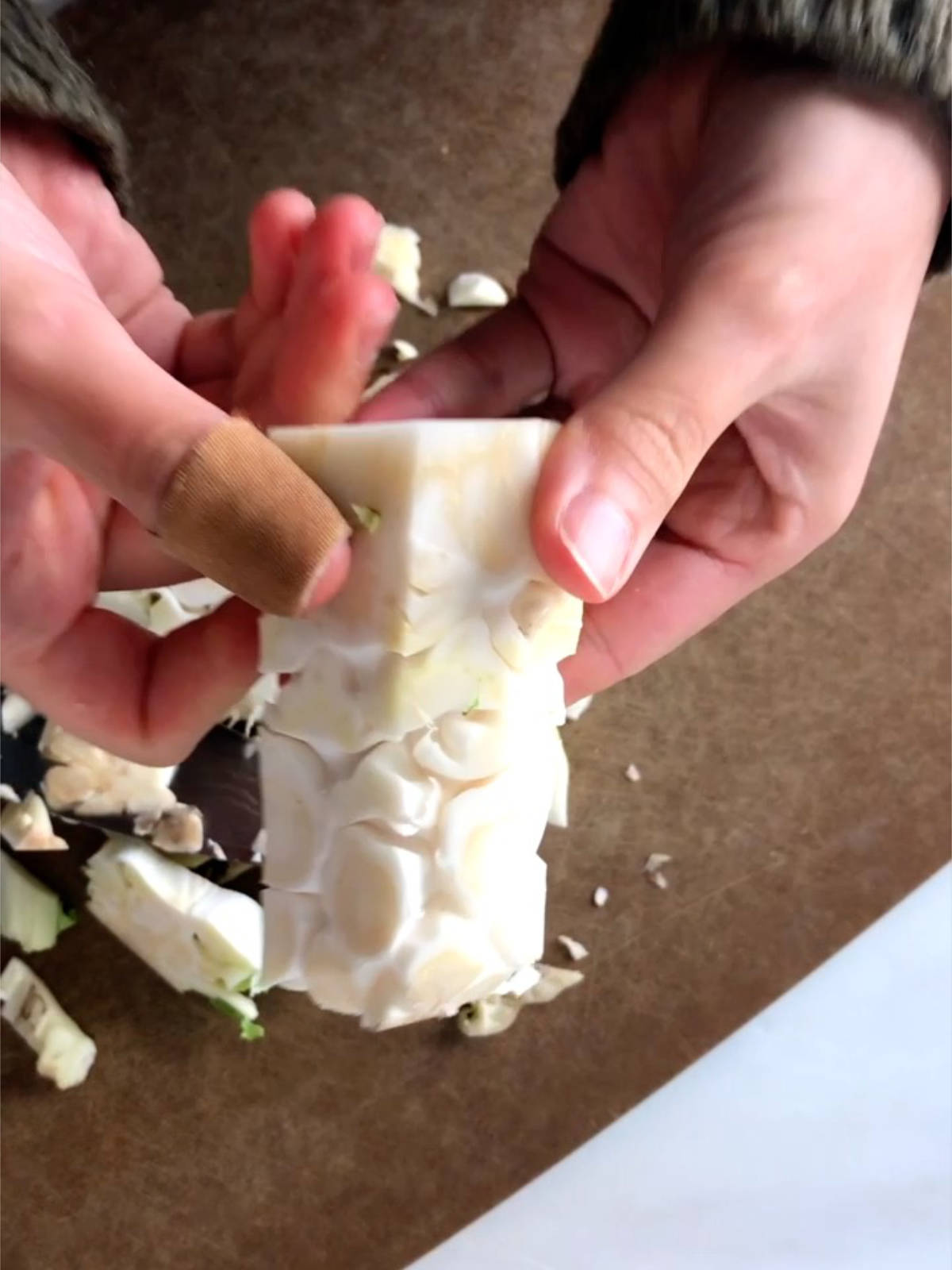 Two hands holding a stalk of cauliflower trimmed down into a pillar.