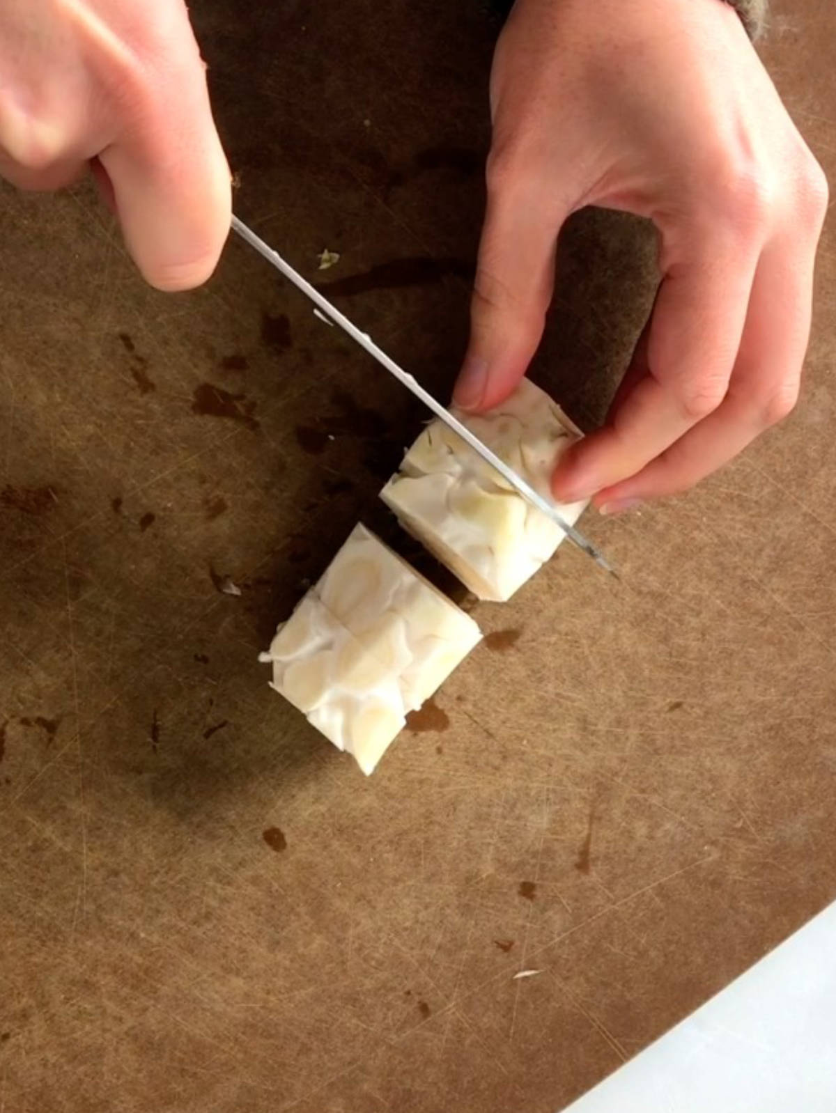 Cutting a stalk of cauliflower into discs with a knife.