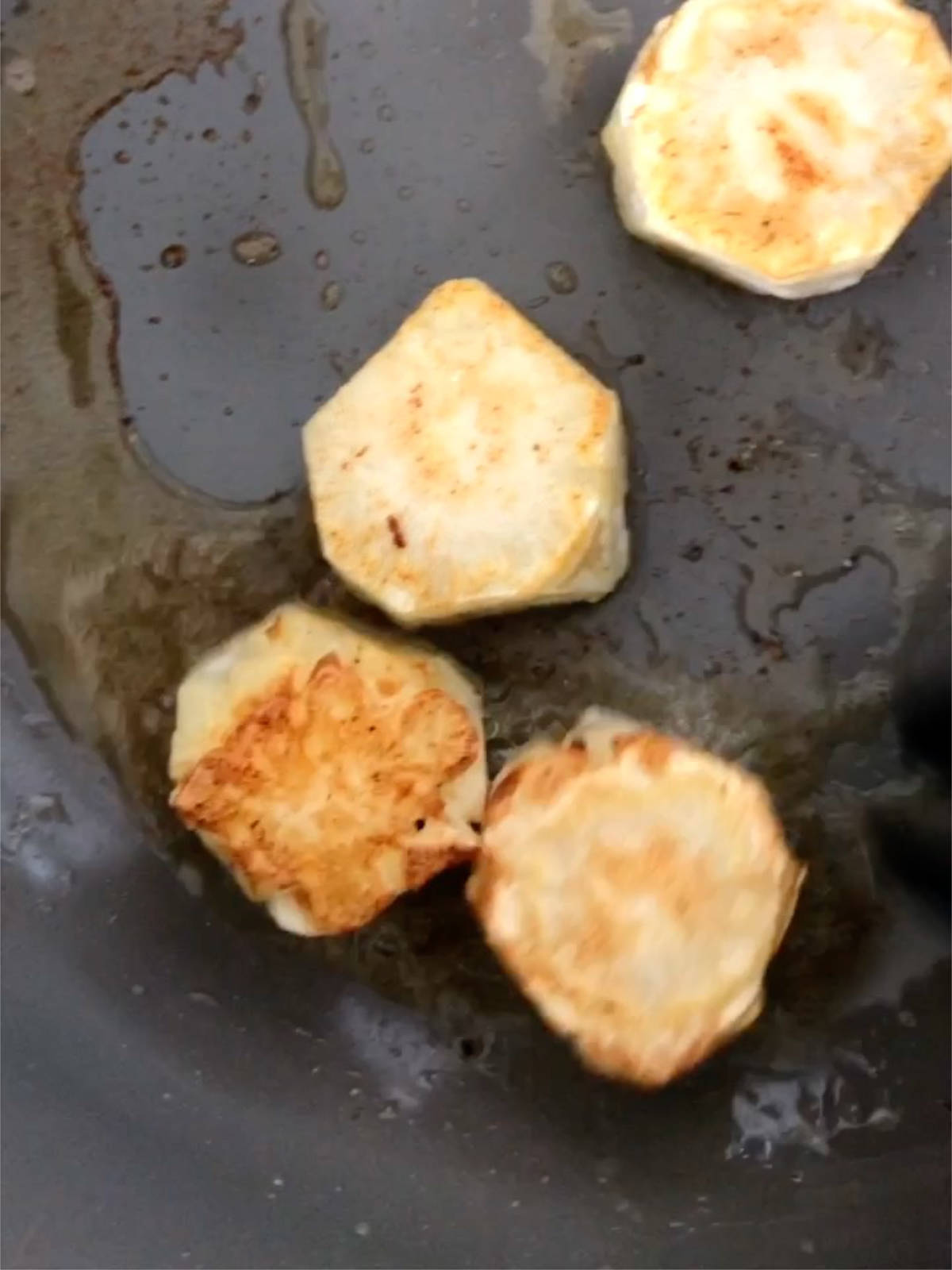 Searing cauliflower discs in a pan until browned.