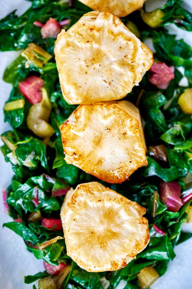 Vegan scallops on a bed of greens.