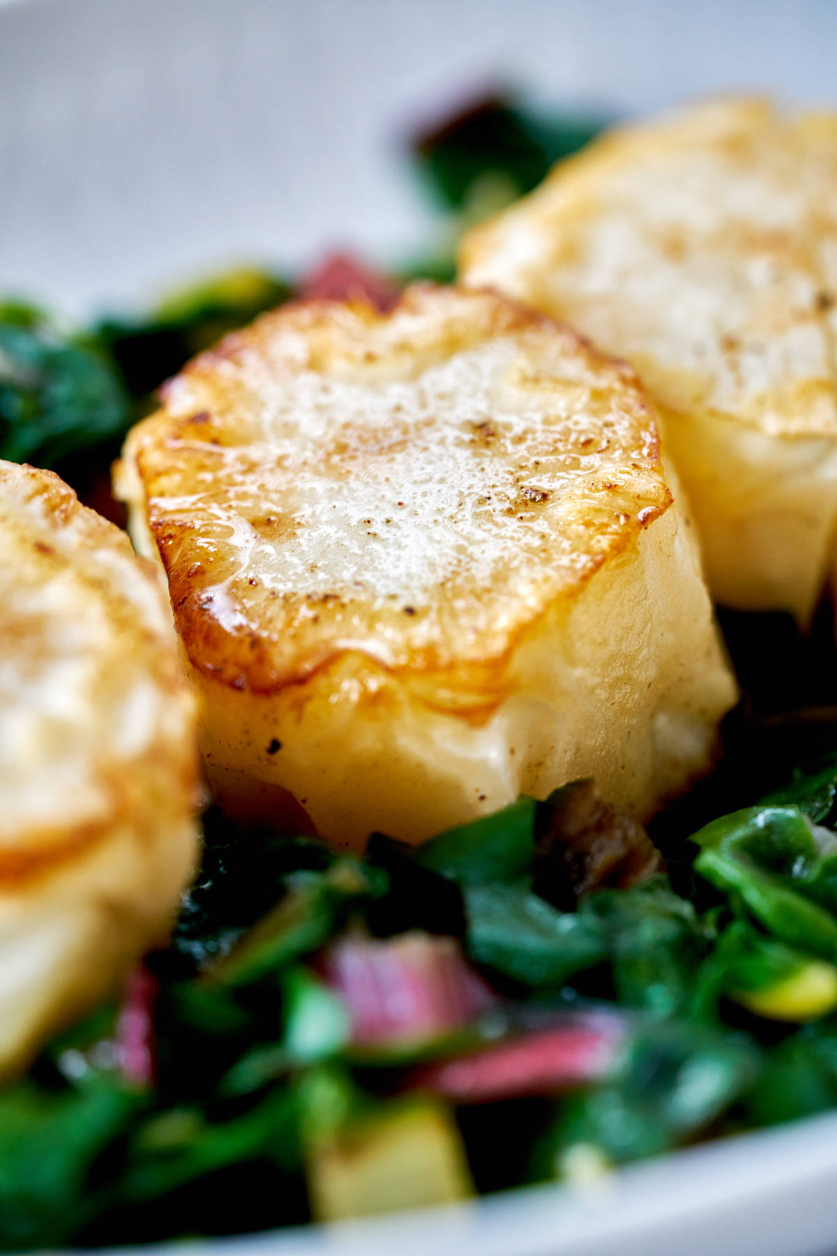 Vegan scallops on a bed of greens.