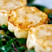 Cauliflower discs on a bed of cooked greens.