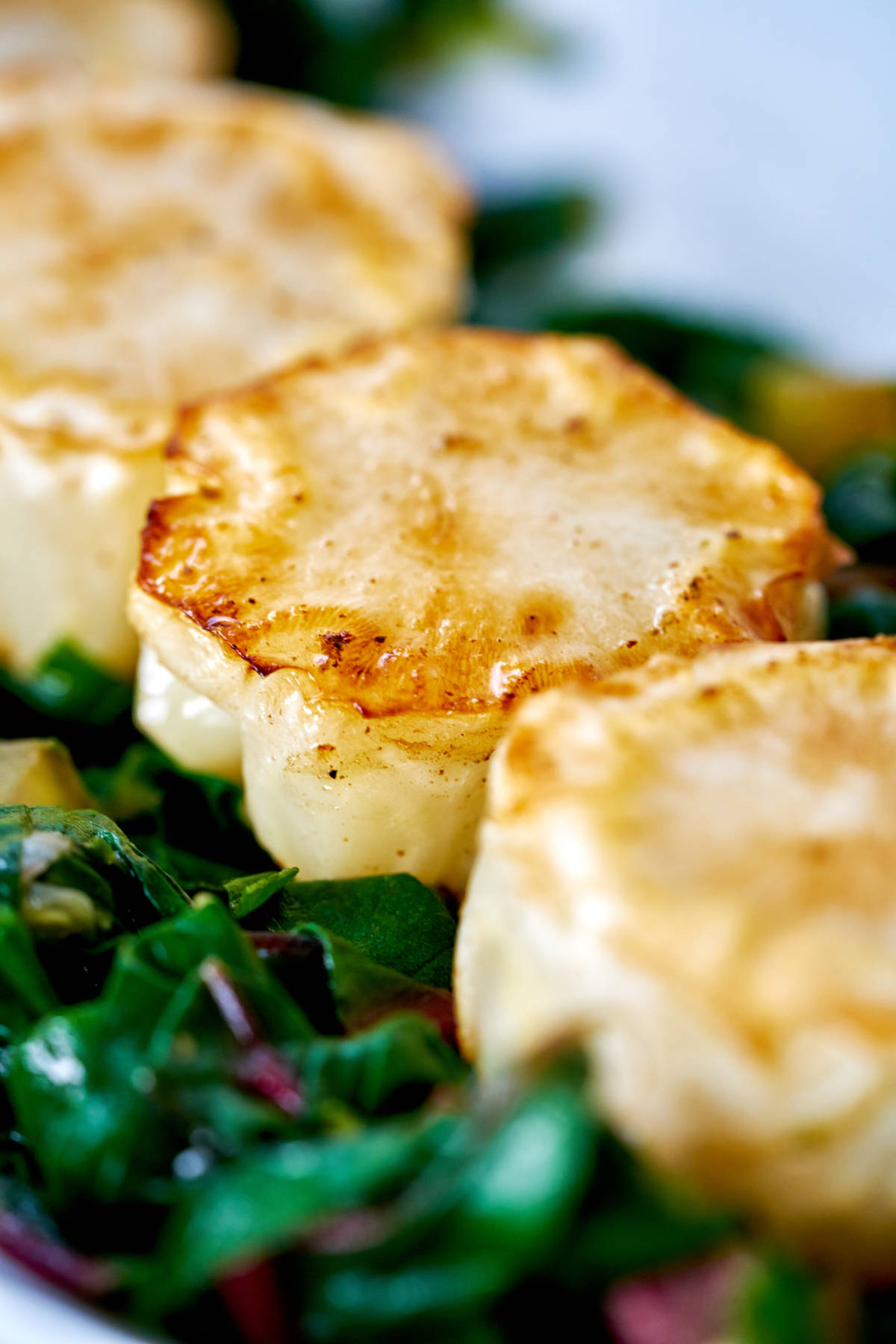 Cauliflower discs on a bed of cooked greens.