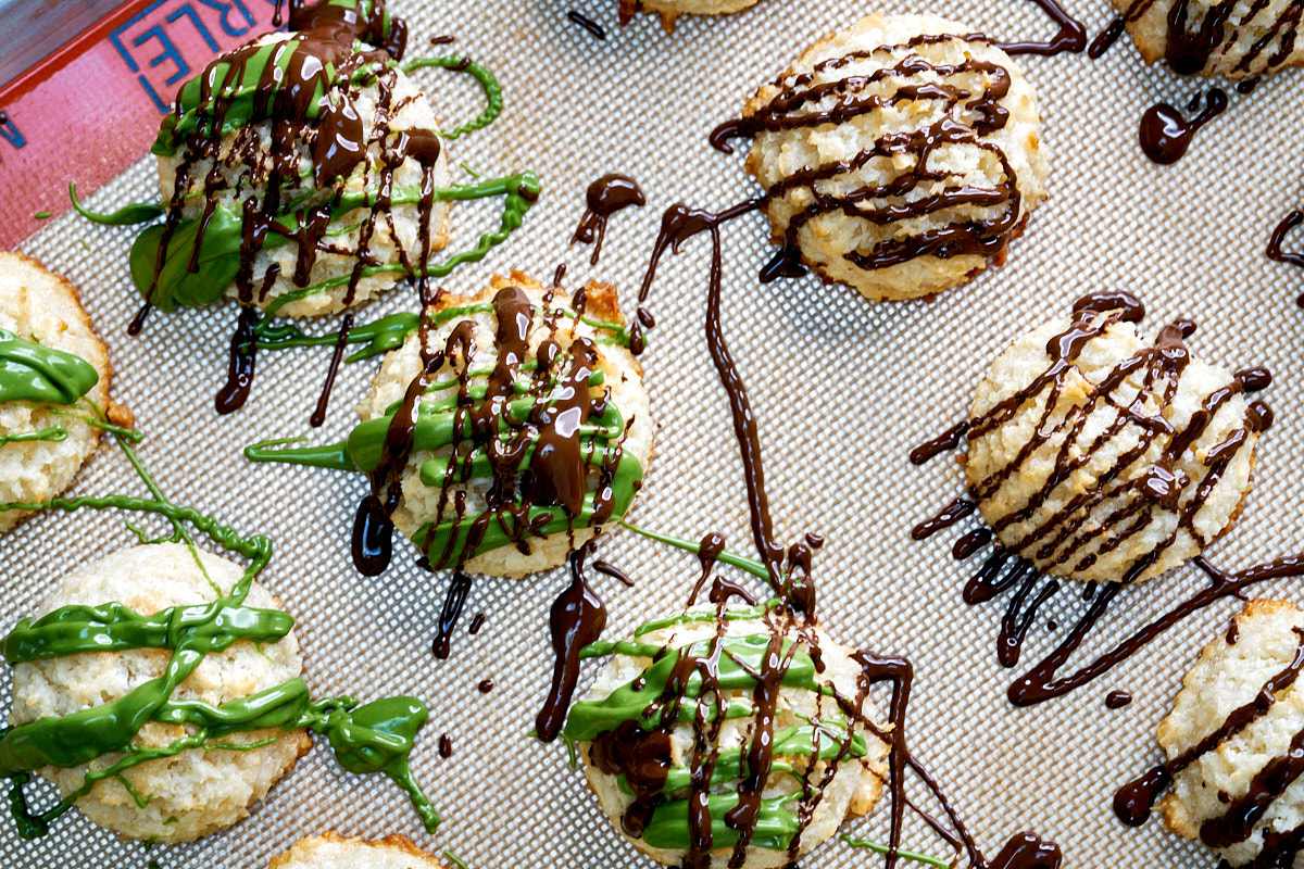 Chocolate drizzled on cookies on a baking sheet.