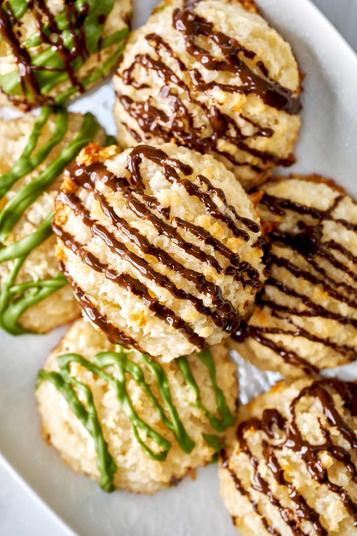 Cookies drizzled with chocolate stacked in a dish.