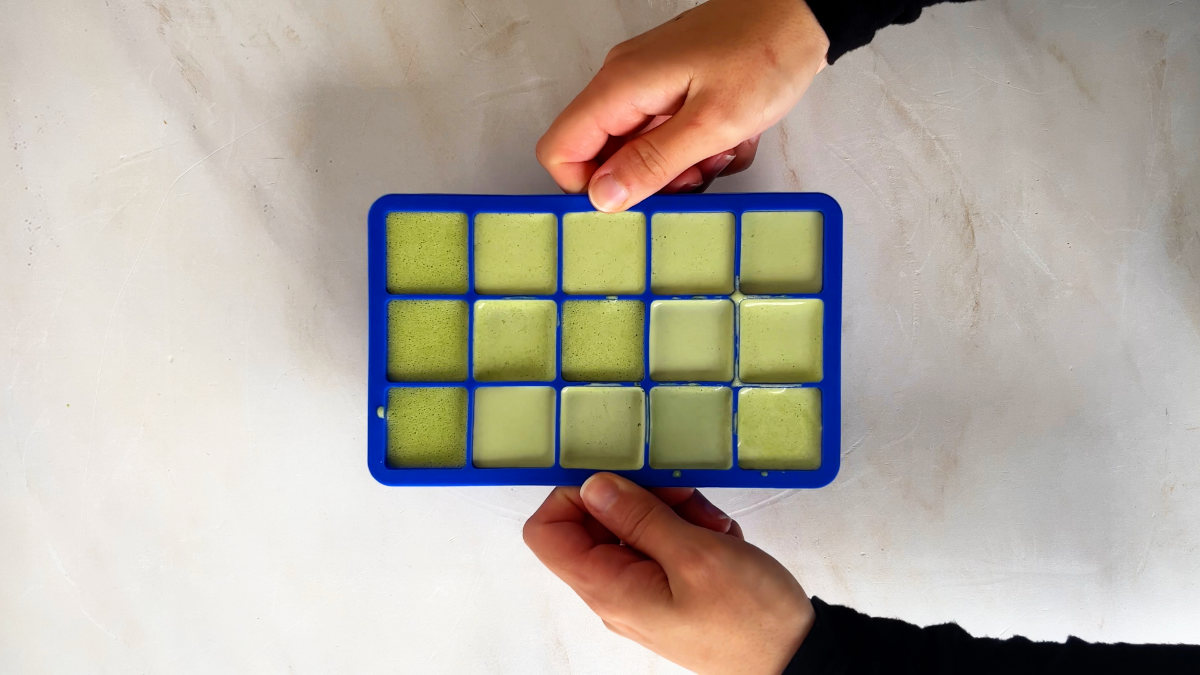 Green ice cubes in a blue ice cube tray.