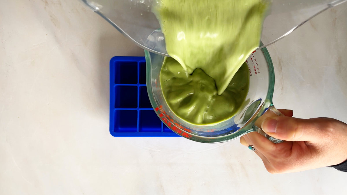 Pouring green liquid into a measuring cup.