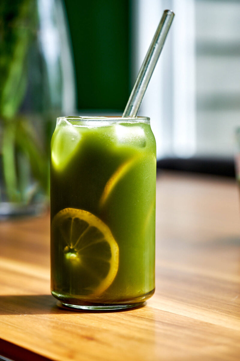 Glass of iced green tea with lemon slices and a straw.
