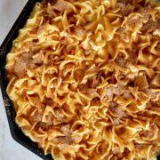 Baked noodle casserole with cinnamon topping in a cast iron pan.
