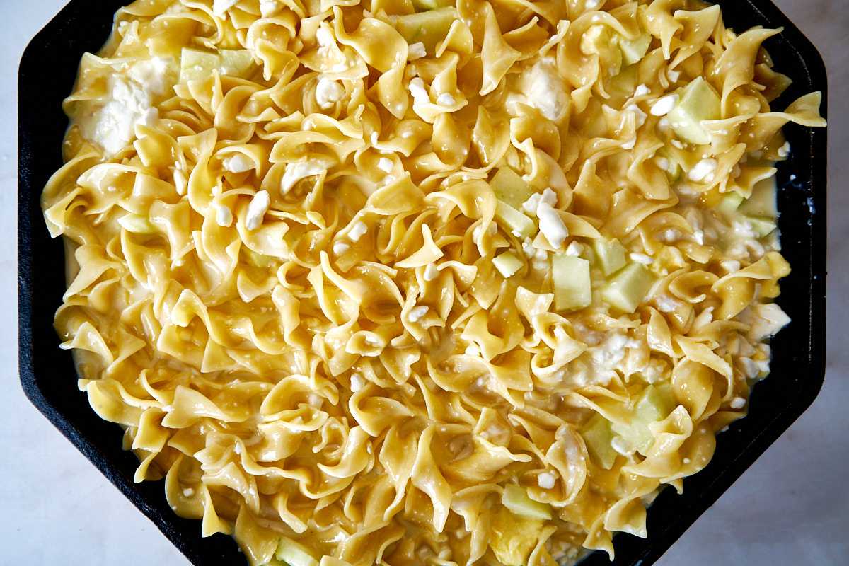 Noodles and apples in a cast iron pan.