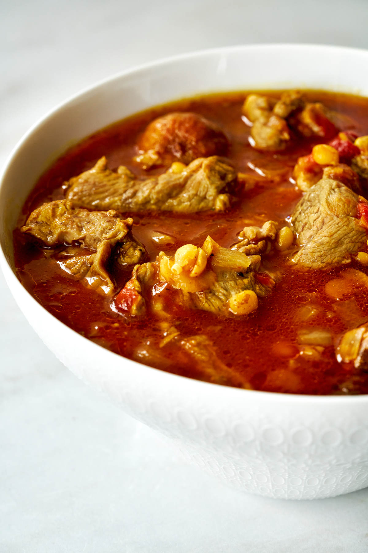 Serving bowl with red meat stew with split peas.