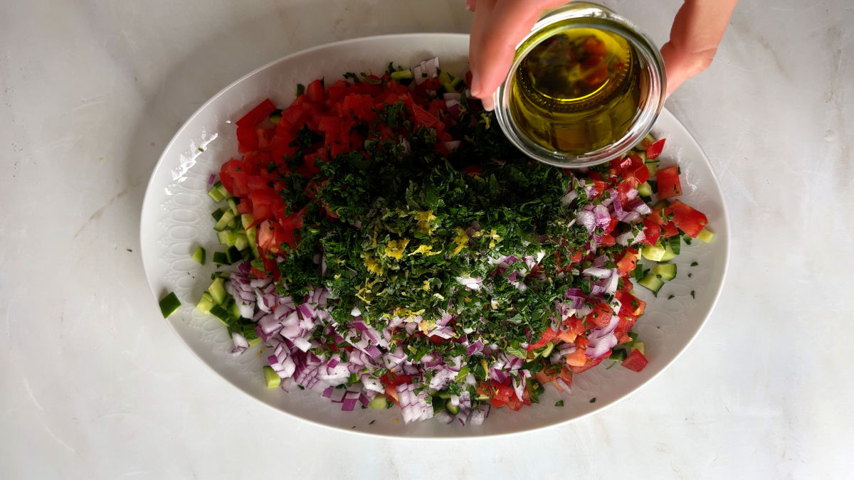 Pouring olive oil on a salad.