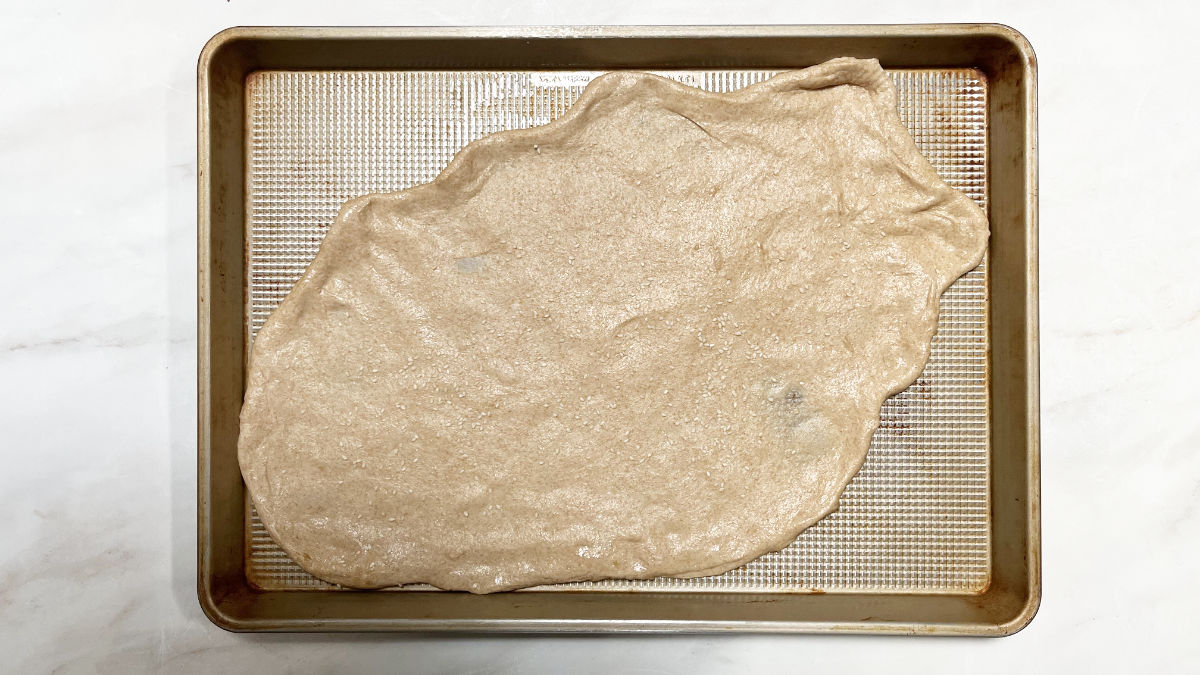 Raw flatbread on a baking sheet.