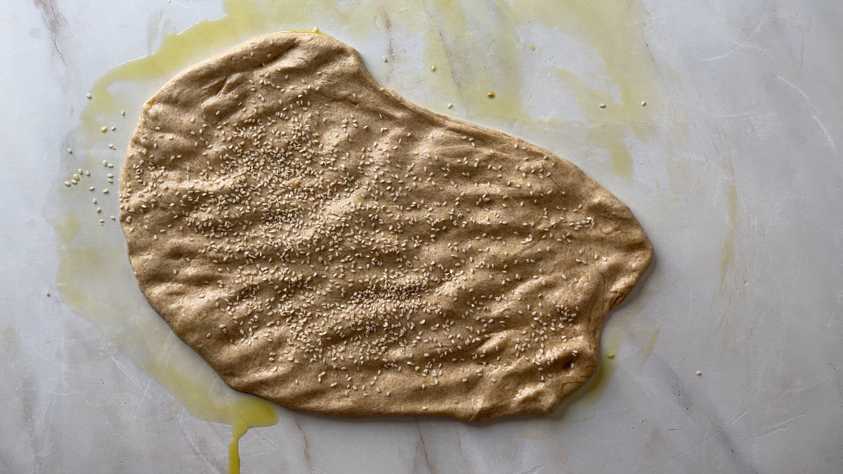 Flattened bread dough with sesame seeds.