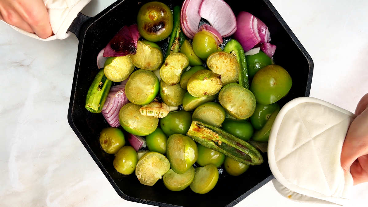 Tomatillos and other vegetables in a cast iron pan.