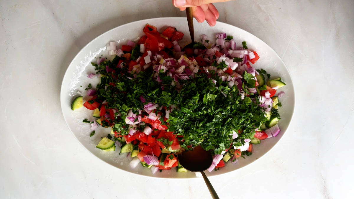 Two spoons mixing a salad together.