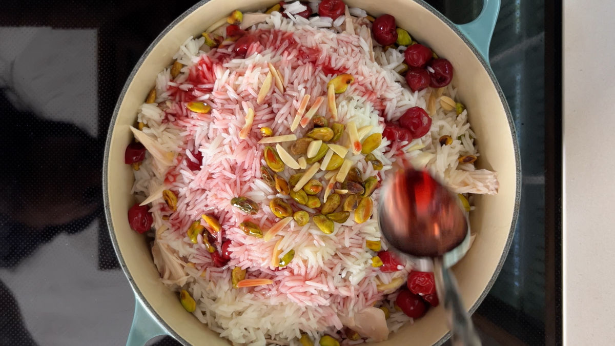 Rice in a pot with red syrup and nuts.