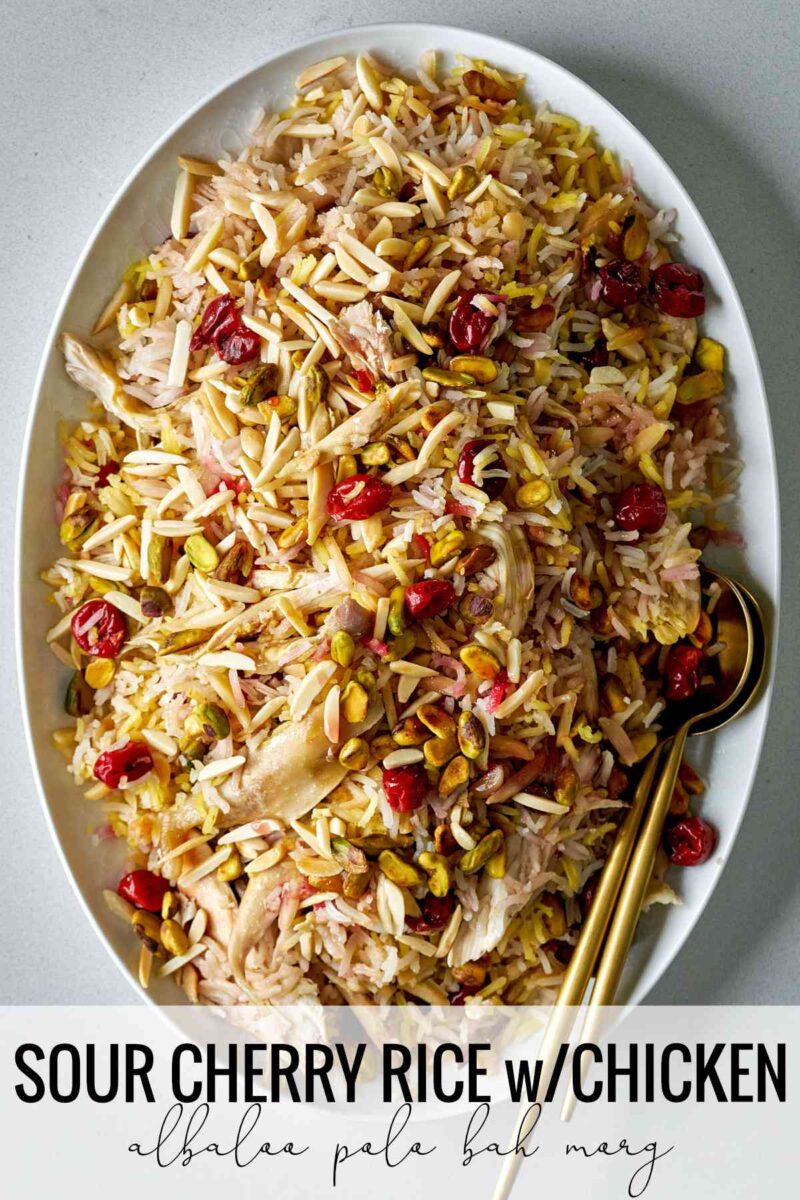 Rice with cherries and nuts on a white serving platter with gold serving spoons and title text.