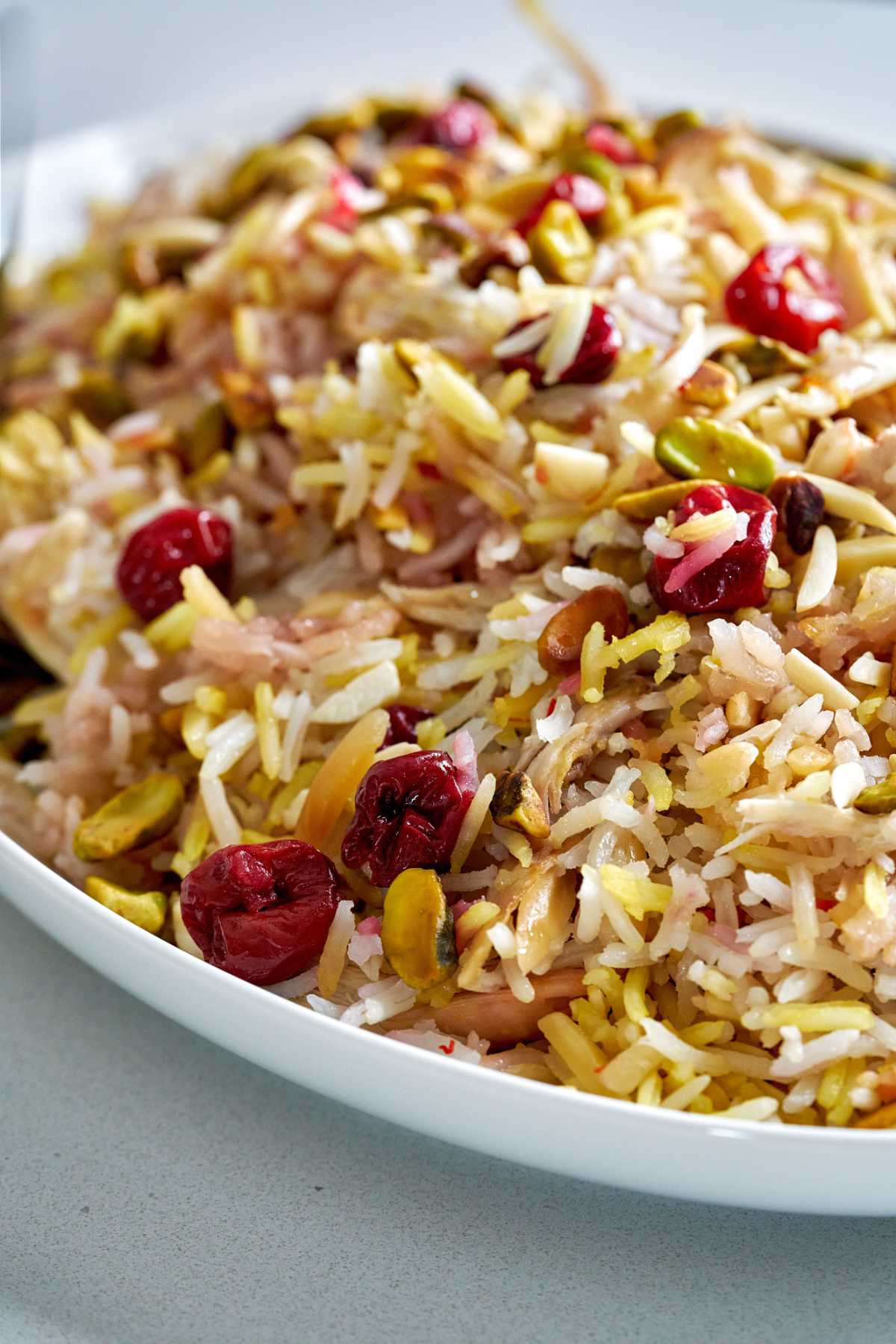 Rice with cherries and nuts on a white serving platter.