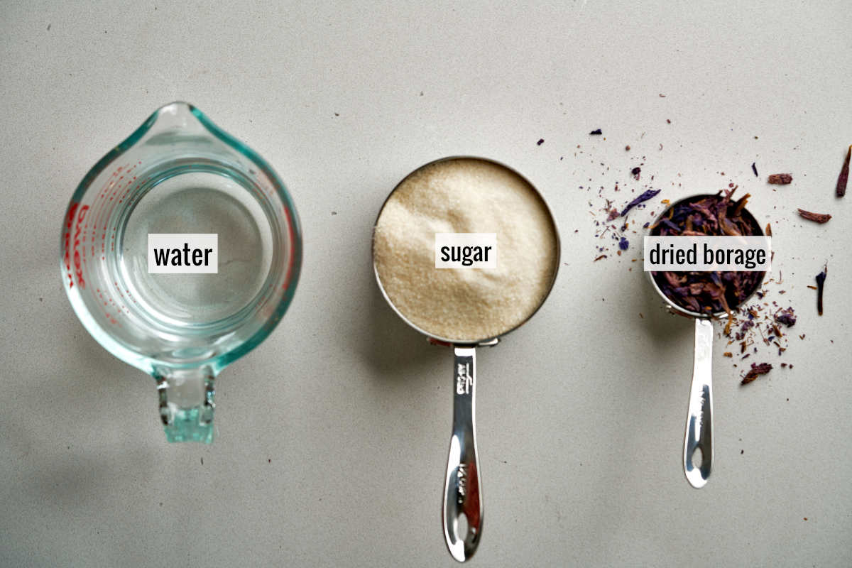 Water, sugar, and borage leaves on a countertop.