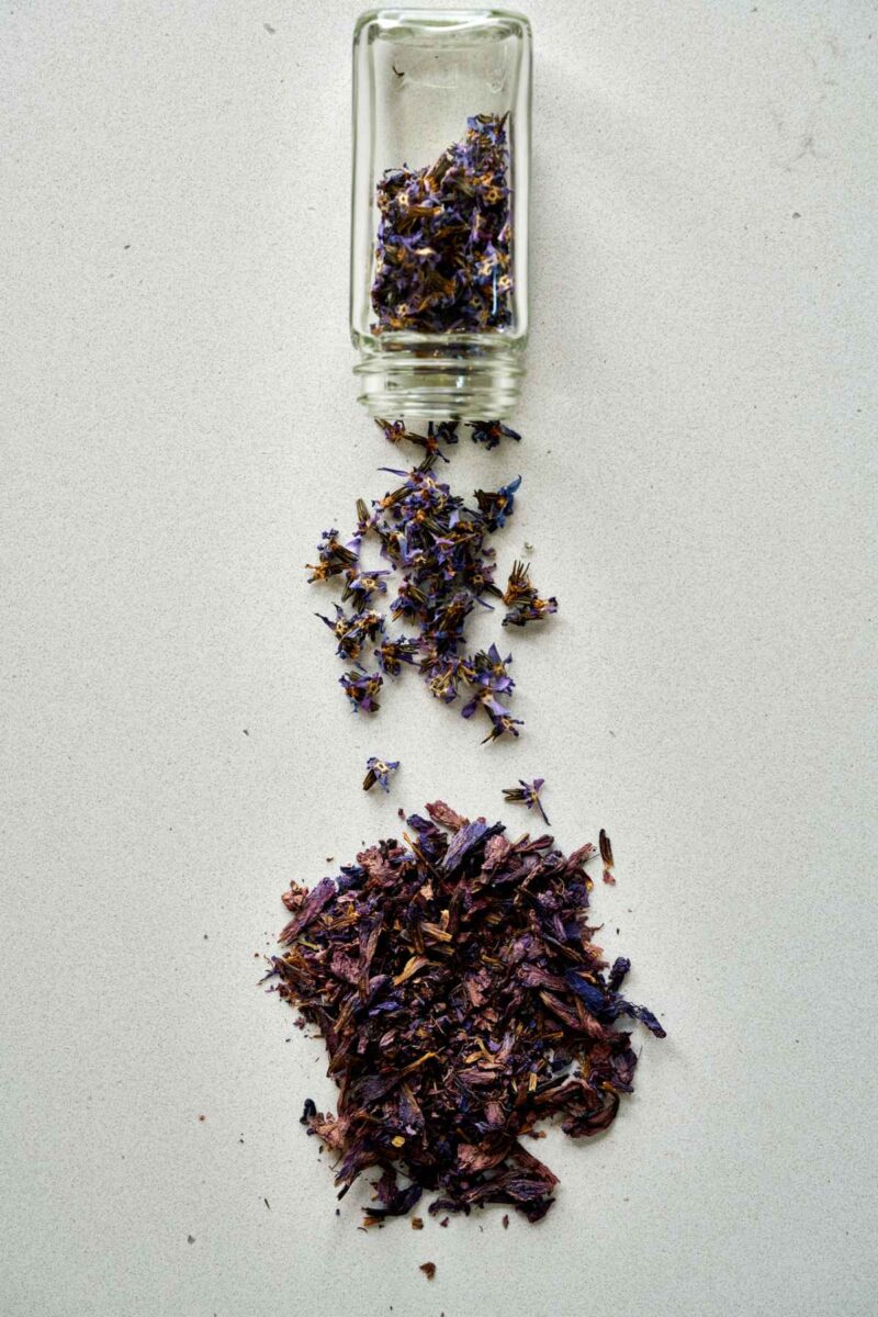 Different kinds of dried borage on a countertop coming out of a jar.