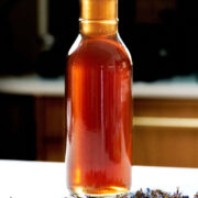 Golden syrup in a jar behind purple flowers.