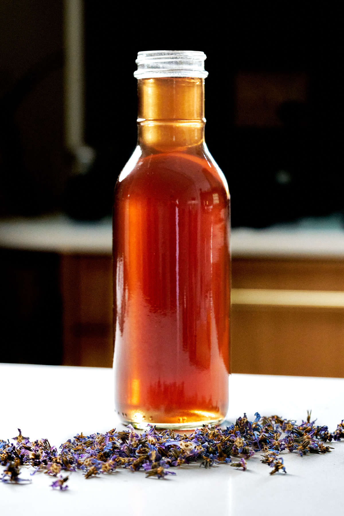 Golden syrup in a jar behind purple flowers.