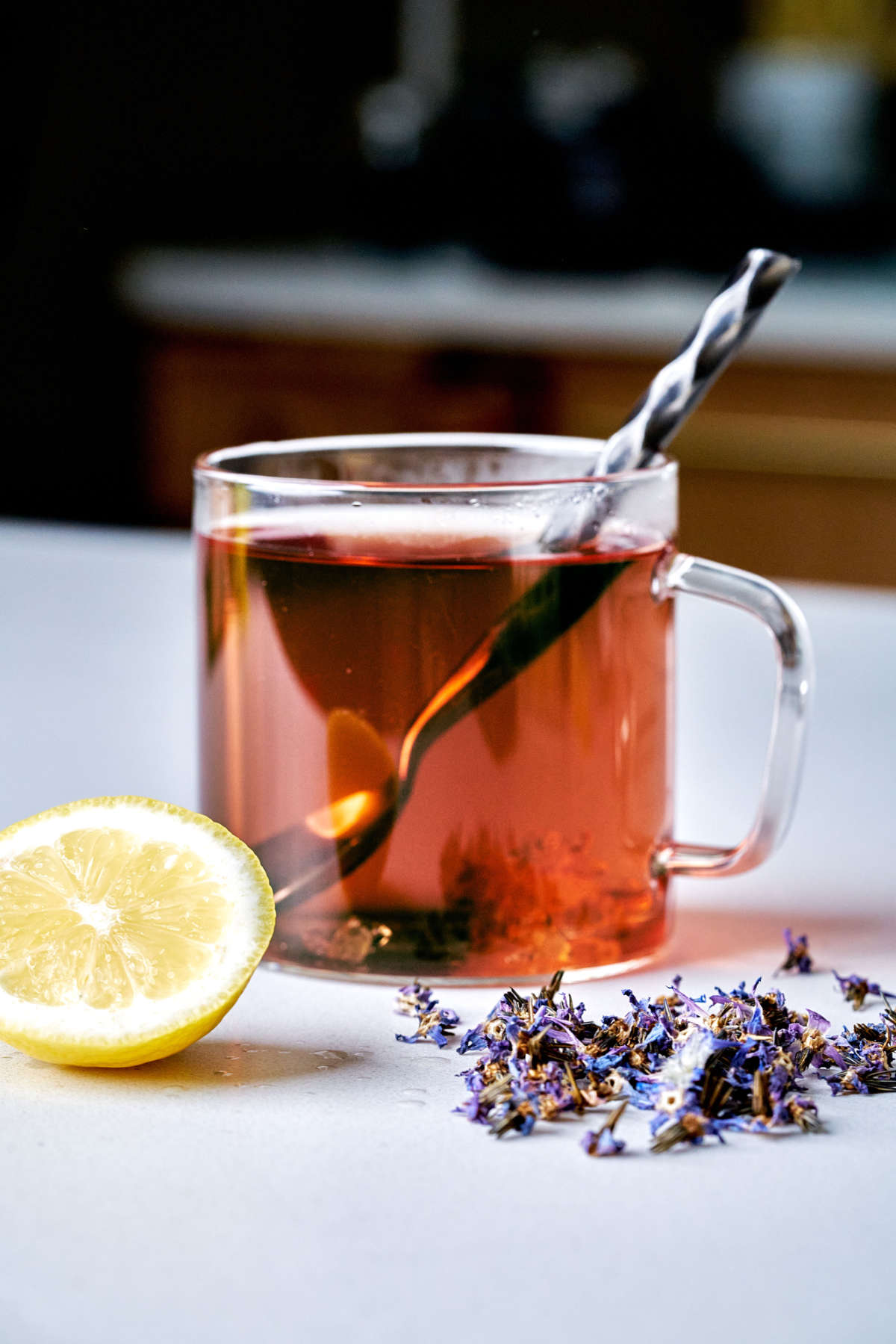 Glass of tea next to lemon and purple flowers.