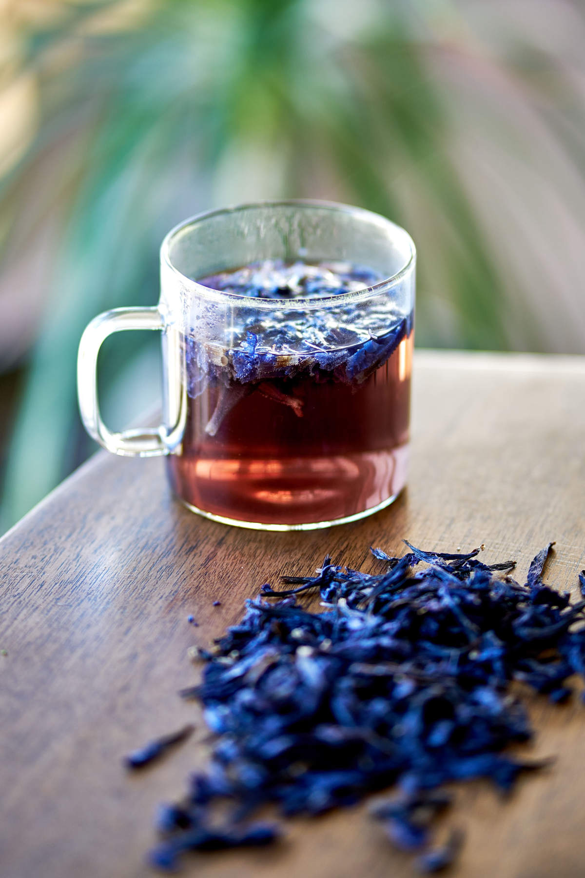 Glass of tea next to a pile of purple flowers.