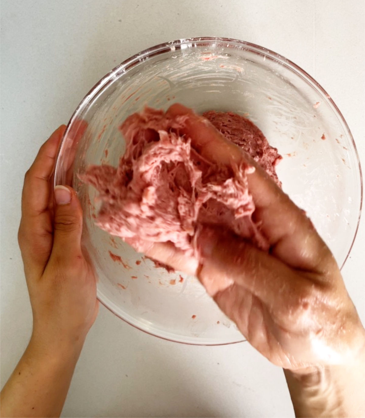 Kneading meat in a glass bowl.