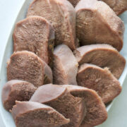 Top view of sliced cow tongue on a plate.